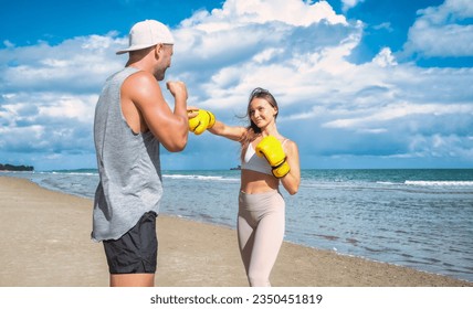 Sport man and woman boxing on beach with blue sky at daytime - Powered by Shutterstock