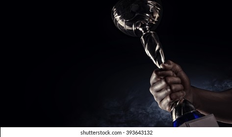 Sport. Man's Hand Holding Up A Gold Trophy Cup As A Winner In A Competition 