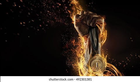 Sport. Man's hand holding up trophy medal. Winner in a competition. Fire and energy - Shutterstock ID 492301381
