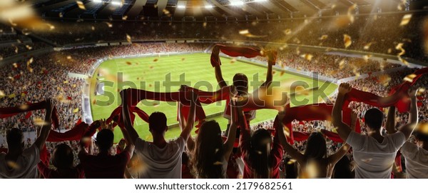 Sport match.\
Back view of football, soccer fans cheering their team with\
colorful scarfs at crowded stadium at evening time. Concept of\
sport, cup, world, team, event,\
competition