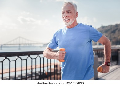 Sport With Me. Confident Senior Unshaken Man Spending Time On Fresh Air Holding Dumbbells And Running.