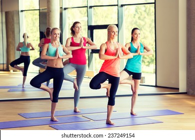sport, meditation and lifestyle concept - smiling women meditating on mat in gym