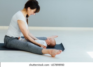 Sport, motherhood and active lifestyle concept -mother having fun and workout with her little son. Gymnastics for newborn baby. Side view - Powered by Shutterstock