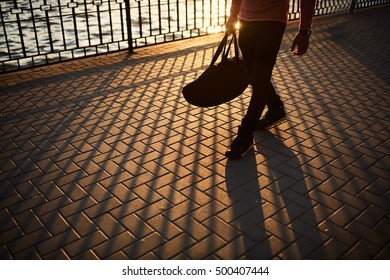 Sport Motivation Concept. Close Up Sports Male Legs Walking On Sunset. Young Man Woke Up In Morning And Going To Gym With A Bag.