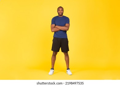 Sport Motivation. Determined African American Sportsman Crossing Hands Posing Looking At Camera Standing On Yellow Studio Background, Wearing Fitwear. Fitness Workout Concept. Full Length - Powered by Shutterstock