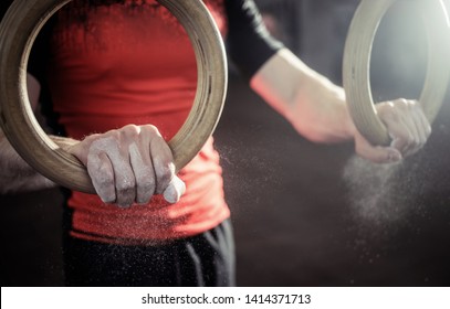 Sport. Muscle-up Exercise Young Man Workout At The Gym On Gymnastic Rings With Magnesia On The Hands. Grop Close-up View.