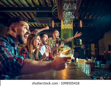 Sport, people, leisure, friendship, entertainment concept - happy male and female football fans or good yuong friends drinking beer, celebrating victory at bar or pub. Human positive emotions concept