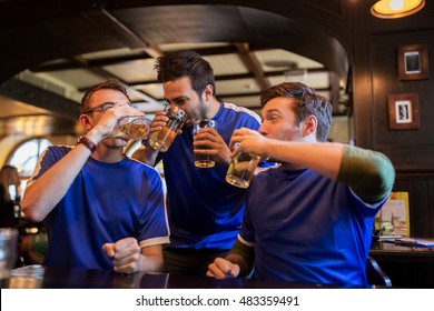 sport, people, leisure, friendship and entertainment concept - happy football fans or male friends drinking beer and celebrating victory at bar or pub