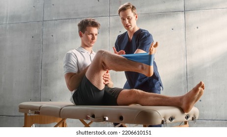 Sport Physiotherapy Specialist Showing How to Stretch a Rubber Band on Specific Muscle Groups or Joints to Young Male Athlete. Sportsman Recovering from Injury, Undergoing Rehabilitation. - Shutterstock ID 2206610151