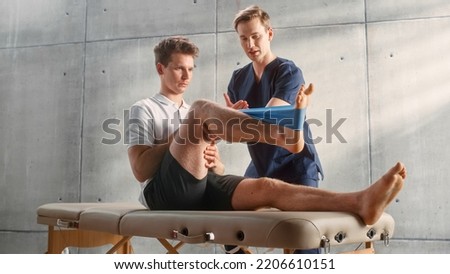 Sport Physiotherapy Specialist Showing How to Stretch a Rubber Band on Specific Muscle Groups or Joints to Young Male Athlete. Sportsman Recovering from Injury, Undergoing Rehabilitation. Foto stock © 