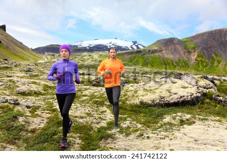 Sport running. Runners on cross country trail outdoors working out for marathon. Fit young fitness model man and asian woman training together outside in mountain nature on Snaefellsnes, Iceland.