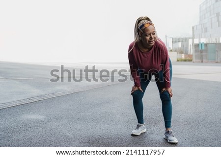 Sport senior African woman running outdoor on rainy day - Focus on face