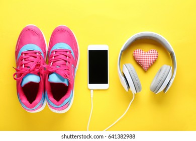 Sport shoes with smartphone and headphones on yellow background - Powered by Shutterstock