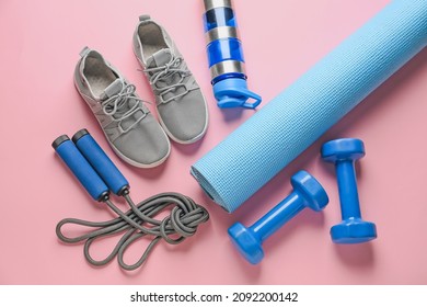 Sport shoes, yoga mat, bottle of water, dumbbells and skipping rope on color background