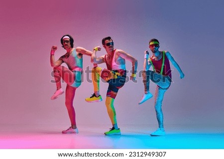 Sport show. Three funny men in colorful sportswear doing aerobics exercises against gradient blue pink studio background in neon light. Concept of sportive and active lifestyle, humor, retro style. Ad