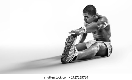Sport. Sprinter doing stretching exercises and smiling on the floor. Isolated on white.