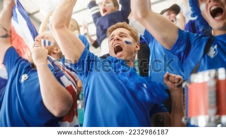 Sport Stadium Event: Crowd of Fans Cheer for their Blue Soccer Team to Win. People Celebrate Scoring a Goal, Championship Victory. Group of Friends with Painted Faces Cheer, Shout, Have Emotional Fun