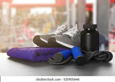 Sport Stuff On Table Against Blurred Gym Interior Background