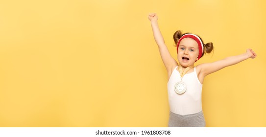 Sport Success And Win Children - Happy Athlete Champion Child Girl Celebrates First Place Victory Gold Medal.Sport Kid Posing Isolated Over Yellow Studio Background With Medal. Banner,mock,copy Space