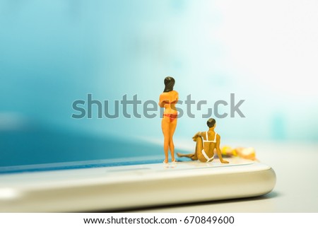 Sport and technology concept. Group of women wearing swimsuit standing, sitting and laying on smart phone screen.