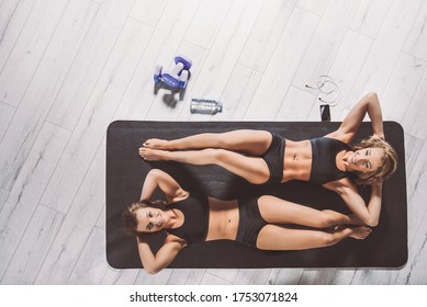 sport together - two girls do crunches sit-ups