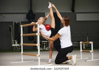 Sport training with coach. Preparing for sport competition. Beginner gymnastics athletes doing exercises with gymnastics equipment at sports gym, indoors. Concept of achievements, studying, goals - Powered by Shutterstock