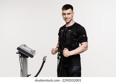 Sport training in electrical muscle stimulation suit. Muscular male athlete in EMS suit on white background