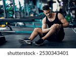 Sport Trauma. Young Arab Male Athlete Touching His Hurted Knee At Gym, Upset Middle Eastern Guy Sitting On Floor And Massaging Sore Injured Leg After Workout Training In Fitness Club, Free Space