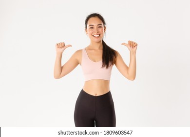 Sport, Wellbeing And Active Lifestyle Concept. Proud And Happy Smiling Asian Female Fitness Instructor, Sportswoman Pointing At Herself, Gaining Workout Goal, Become Gym Member, White Background