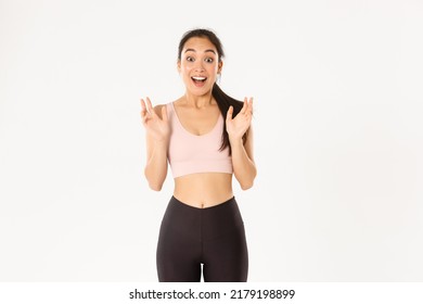 Sport, wellbeing and active lifestyle concept. Happy enthusiastic fitness girl, asian sportswoman clasp hands from fantastic news, gasping amazed, standing over white background - Shutterstock ID 2179198899