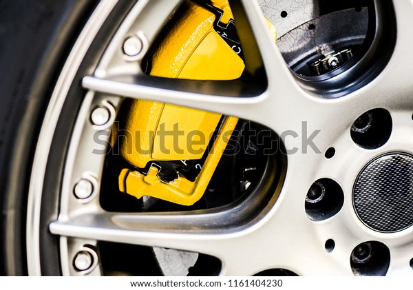 Sport  wheel rim close up. Detail of yellow\
new brake pads changed on luxury\
car.