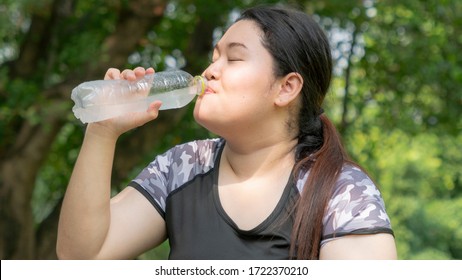 Sport Woman. Asian Sport Fat Girl Drink Water From Plastic Bottle On The Hand In Summer Hot Day At Outdoor Garden