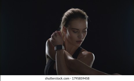 Sport woman doing stretch exercise on black background in studio. Fit girl warming up before sport workout. Fitness model stretching hands while warm up gym in dark studio. Fitness lifestyle