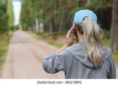 Sport Woman Talking On Phone Outdoors. Back View