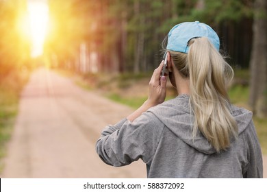 Sport Woman Talking On Phone Outdoors. Back View