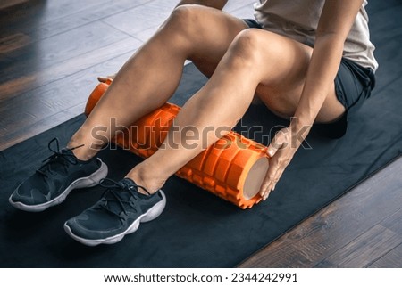 Sport woman using foam roller for muscle and fascia stretching foot.