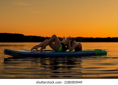 Sport woman yogini scorpion pose practice yoga exercise on sup board on the sea in relaxing day , yoga is meditation and healthy sport concept.yoga on a paddle board