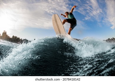 Sporting energy young man having fun and jumping up on wakesurf board on river wave - Powered by Shutterstock