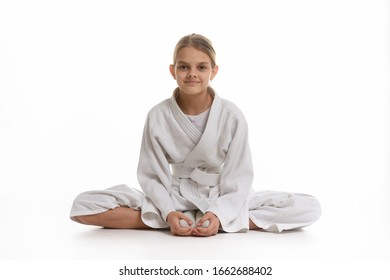 Sporting Girl In Keikogi Sits On The Floor, White Background