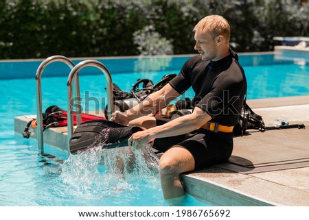 The sporting man puts fins on foot before swim in the pool