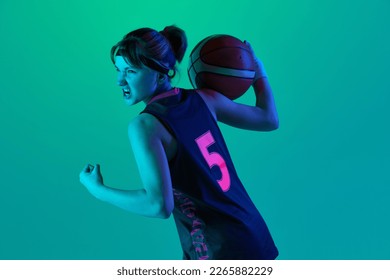 Sportive ambitions and motivation. Teen girl, basketball player posing with ball isolated over gradient green background in neon light. Concept of sportive lifestyle, active hobby, health, competition - Powered by Shutterstock