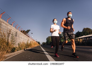 Sportive Asian man and woman in face mask running on street together during Coronavirus or Covid-19 outbreak. Runner couple jogging during quarantine. wide angle - Powered by Shutterstock