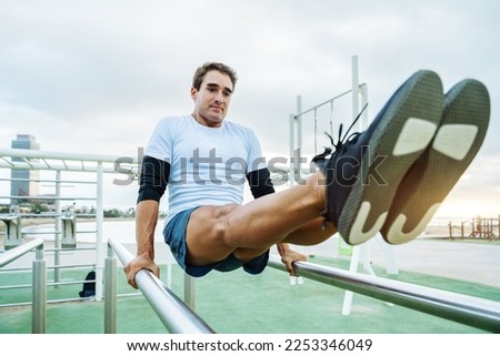 Sportive and athletic man does functional training exercise at the outdoor gym - Adult athlete doing workout at sunrise at calisthenics park on the beach - Fitness, healthy lifestyle and sport concept