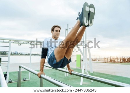 Sportive athletic man doing functional training exercise at the outdoor gym - Adult athlete doing workout at sunrise at calisthenics park on the beach - Fitness, healthy lifestyle and sport concepts