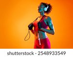 Sportive black hispanic woman wearing sportswear training in fitness studio, colorful dramatic lighting - African-american female athlete doing sport workout