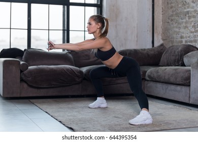 Sportive Caucasian Female Athlete In Black Sports Bra And Leggings Doing Side Squat Exercise At Home