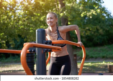 Sportive Female Training Dip Exercise Machine Outdoor Gym Summer Park Middle Age Caucasian Woman Dressed Sportswear Workout Outside On Simulator Sport Ground. Healthy Lifestyle Concept