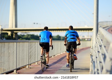 Sportive Men Cycling By Ada Bridge Over The Sava River In Belgrade, Serbia, On Hot Summer Day. Nice Sport For Active People. Healthy Lifestyle. Tourism And Travel In Europe.