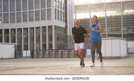 Sportive Middle Aged Couple Jogging Together In The Morning While Training Outdoors