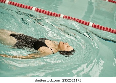 sportive middle aged woman swimming on back in pool, swim cap and goggles, sport, healthy lifestyle - Powered by Shutterstock